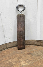 Load image into Gallery viewer, Whiskey barrel stave handled bottle opener, standing on top of a whiskey bottle. Shows the front of the opener.