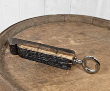 Load image into Gallery viewer, Whiskey barrel stave handled bottle opener, laying on top of a whiskey bottle. Shows the back of the opener.