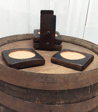 Load image into Gallery viewer, A top view of four coasters fashioned from whiskey barrel staves displaying two coasters on top of a rustic whiskey barrel.